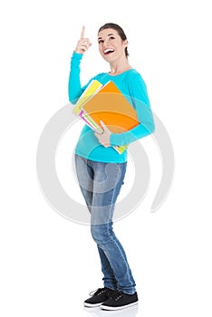 Young beautiful student woman holding workbook and pointing up.