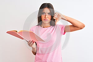 Young beautiful student woman reading book standing over isolated white background with angry face, negative sign showing dislike