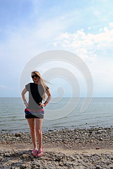 Young beautiful stylish girl in a simple black t-shirt posing near the sea