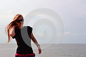 Young beautiful stylish girl in a simple black t-shirt posing near the sea