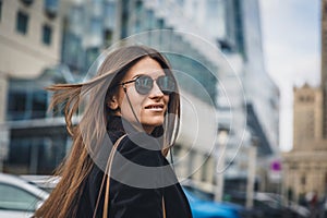 Young beautiful stylish girl in Sunglasses walking on street. Close up portrait of woman is turn around at camera and