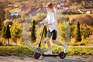 Young beautiful stylish woman riding electric scooter to work, modern girl, electric transport, ecological transport