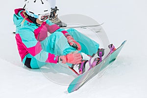 Young beautiful stylish woman strapping on her snowboard
