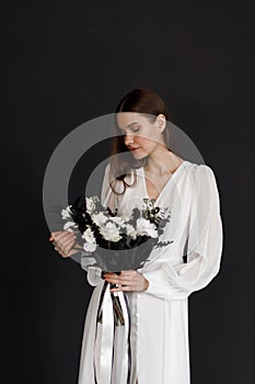 Young beautiful stylish woman, wedding fashion, spring trend, black bouquet of flowers. Bride in a white dress, tenderness,