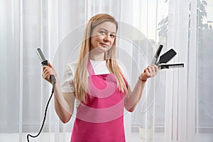 Young beautiful stylist standing holding brushes