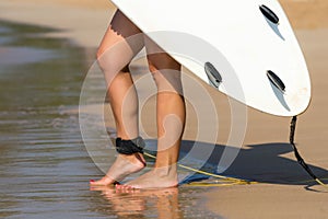 Young beautiful surfer girl on beach with surf board at day break