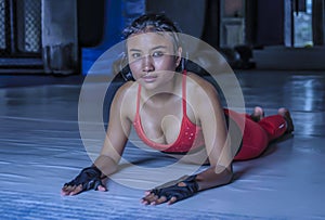 Young beautiful sweaty Asian woman in sport clothes stretching on gym dojo floor smiling posing corporate in hard training workout