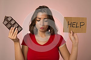 young beautiful sweet addict woman holding asking for help resisting temptation to eat chocolate bar and break diet photo