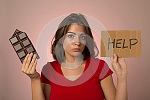 young beautiful sweet addict woman holding asking for help resisting temptation to eat chocolate bar and break diet photo