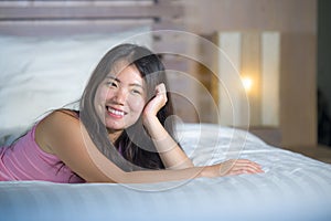 Young beautiful and sweet Asian Chinese woman lying playful and comfortable in bed relaxed and happy at her cozy bedroom smiling c