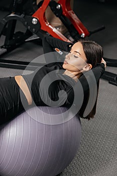 Young beautiful tanned woman doing fitness exercises with a ball