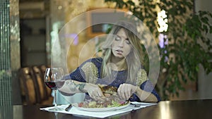 Young beautiful tattooed blond girl in fancy dinner restaurant tearing meat eating with fingers inappropriate behaviour