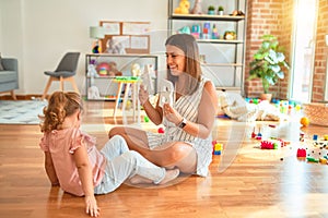 Young beautiful teacher teaching alphabet to blond student toddler girl at kindergarten