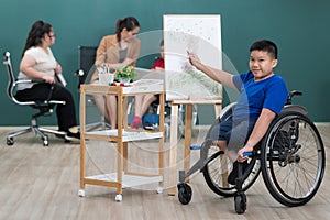 Young and beautiful teacher teaching cute down syndrome girl while disabled boy on wheelchair painting and drawing on paper in