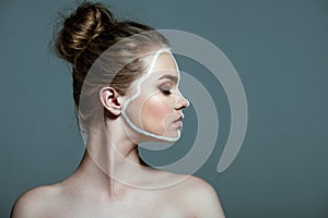 Young beautiful teen girl with closed eyes and creative white body art line on face,