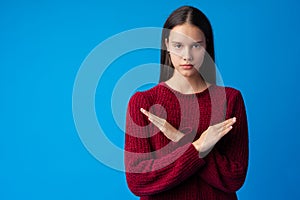 Young beautiful teen girl crossing arms doing negative sign on blue background