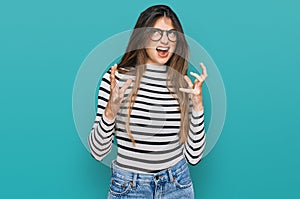 Young beautiful teen girl wearing casual clothes and glasses crazy and mad shouting and yelling with aggressive expression and