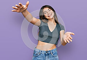 Young beautiful teen girl wearing casual crop top t shirt looking at the camera smiling with open arms for hug