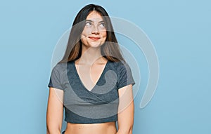 Young beautiful teen girl wearing casual crop top t shirt smiling looking to the side and staring away thinking