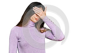 Young beautiful teen girl wearing turtleneck sweater covering eyes with hand, looking serious and sad