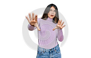 Young beautiful teen girl wearing turtleneck sweater doing stop gesture with hands palms, angry and frustration expression