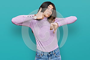 Young beautiful teen girl wearing turtleneck sweater doing thumbs up and down, disagreement and agreement expression