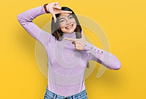 Young beautiful teen girl wearing turtleneck sweater smiling making frame with hands and fingers with happy face