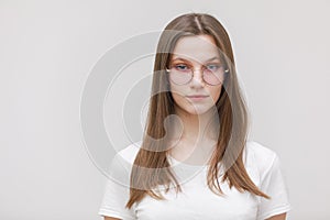 Young beautiful teen girl wearing white t shirt and glasses over white background Relaxed with serious expression on face. Simple