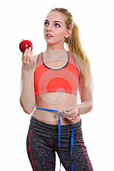 Young beautiful teenage girl holding red apple while thinking an
