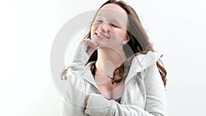 Young beautiful teenage girl on a white background smiles with her eyes closed, tenderness of youth, virginity, purity