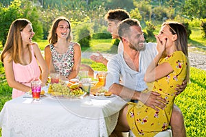 Young beautiful teenager friends enjoying picnic on party outdoor in park.
