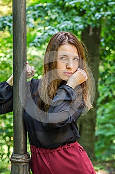 Young beautiful teenager girl with long hair walking in Striysky park in Lviv, posing near a lamp to illuminate the bushes and