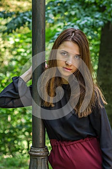 Young beautiful teenager girl with long hair walking in Striysky park in Lviv, posing near a lamp to illuminate the bushes and