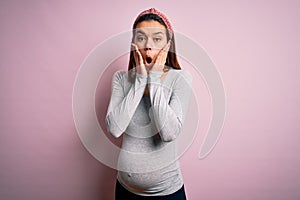 Young beautiful teenager girl pregnant expecting baby over isolated pink background afraid and shocked, surprise and amazed