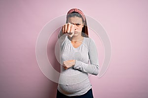 Young beautiful teenager girl pregnant expecting baby over isolated pink background Punching fist to fight, aggressive and angry