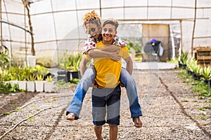 Young beautiful teenager play with his mother middle age pretty woman carrying her to his back. couple mother son having fun