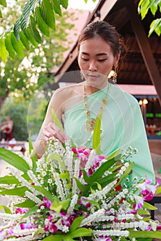 Young Beautiful Thai Asian woman dressing in vintage retro Traditional Thai costume arranging flower vase. Thailand Cultural and