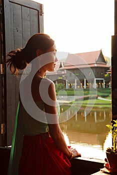 Young Beautiful Thai Asian woman dressing in vintage retro Traditional Thai costume looking out of window. Thailand Cultural and