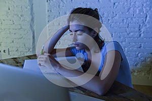Young beautiful and tired student girl sleeping taking a nap lying on home laptop computer desk exhausted and wasted spending nigh