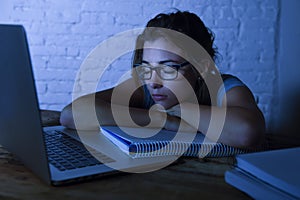 Young beautiful and tired student girl sleeping taking a nap lying on home laptop computer desk exhausted and wasted spending nigh