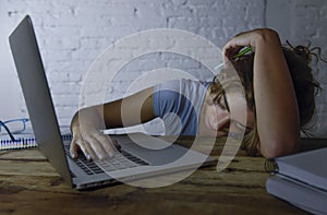 Young beautiful and tired student girl sleeping taking a nap lying on home laptop computer desk exhausted and wasted spending nigh