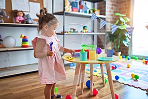 Young beautiful toddler playing with cutlery and food toys on the table at kindergaten