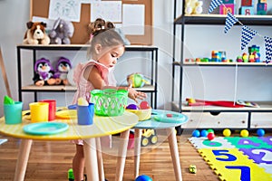 Young beautiful toddler playing with cutlery and food toys on the table at kindergaten