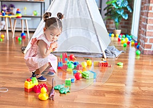 Young beautiful toddler sitting on the floor playing with small cars toys at kindergaten