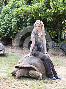 Young beautiful tourist woman riding on giant turtle