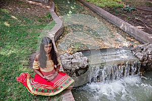 Young beautiful traditional indian woman practicing yoga in nature