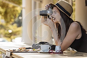 Young beautiful traveler happily taking photos with camera at ca