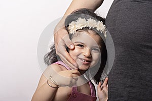 A young beautiful two years old girl portrait with her pregnant mother belly