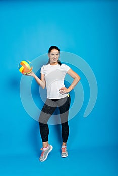 Young beautiful volleyball player isolated on blue in studio