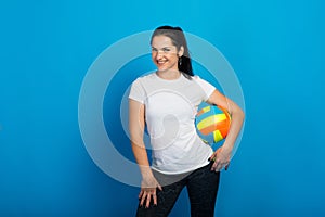 Young beautiful volleyball player isolated on blue in studio